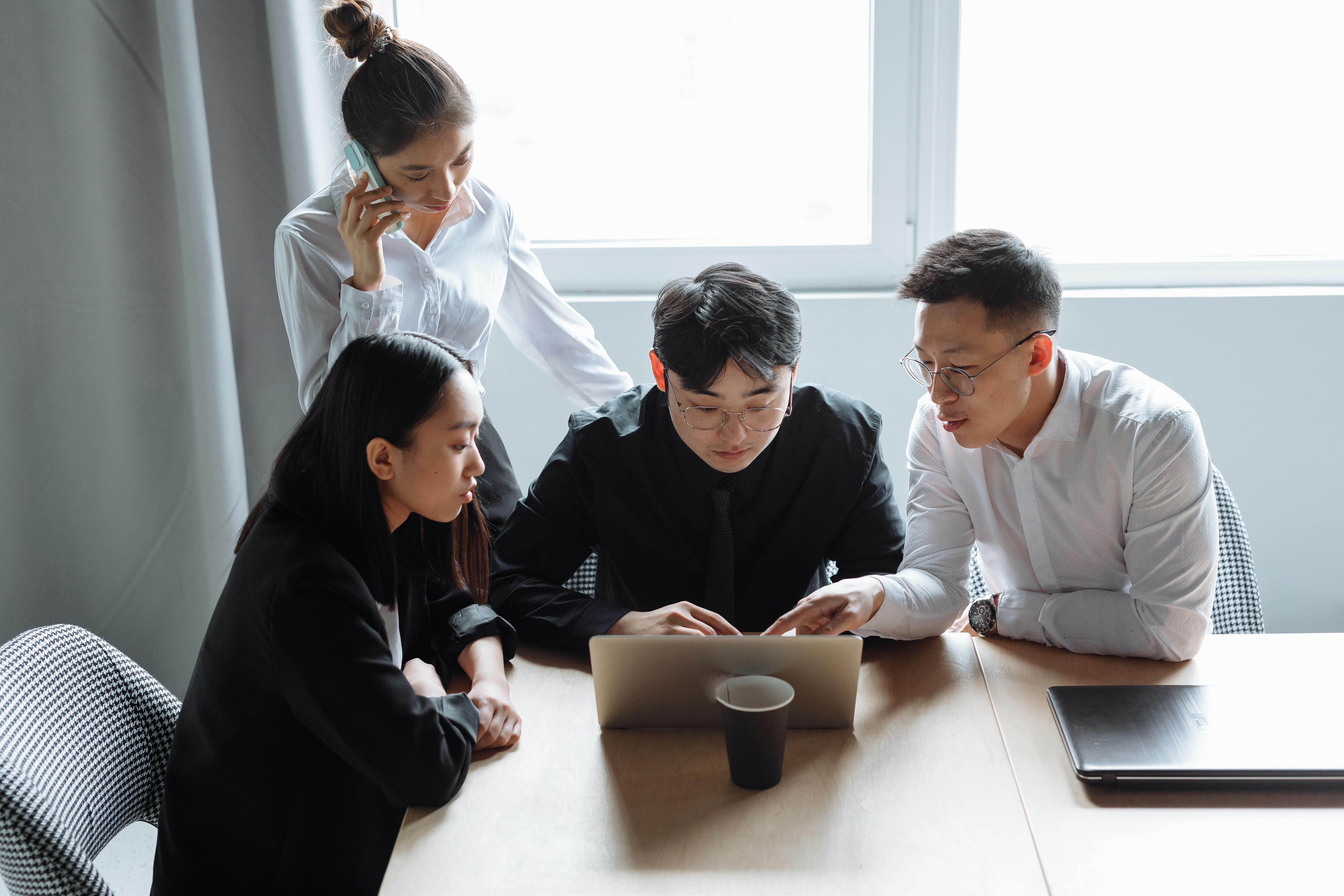 Outsourcing support team collaborating around a laptop